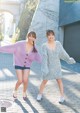 A couple of women standing next to each other on a sidewalk.