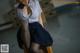 A woman in a school uniform sitting on a chair.