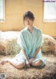 A woman sitting on a pile of hay in a room.