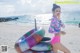 A woman in a pink bikini standing on a beach next to an inflatable ring.