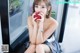 A woman sitting in front of a refrigerator eating an apple.