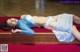 A woman laying on a wooden bench in a room.