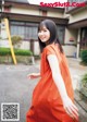 A woman in an orange dress is walking down the street.