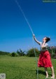 A woman in a red skirt is spraying water on her face.