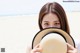 A woman holding a straw hat over her face.