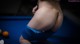 A woman in a bikini standing next to a pool table.