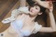 A woman laying on a wooden floor wearing a white bra.